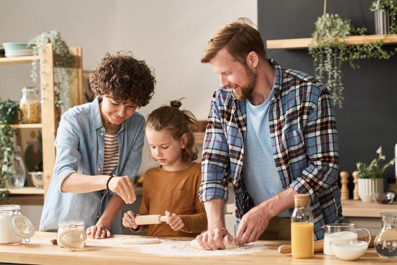 parents teaching child to bake pie